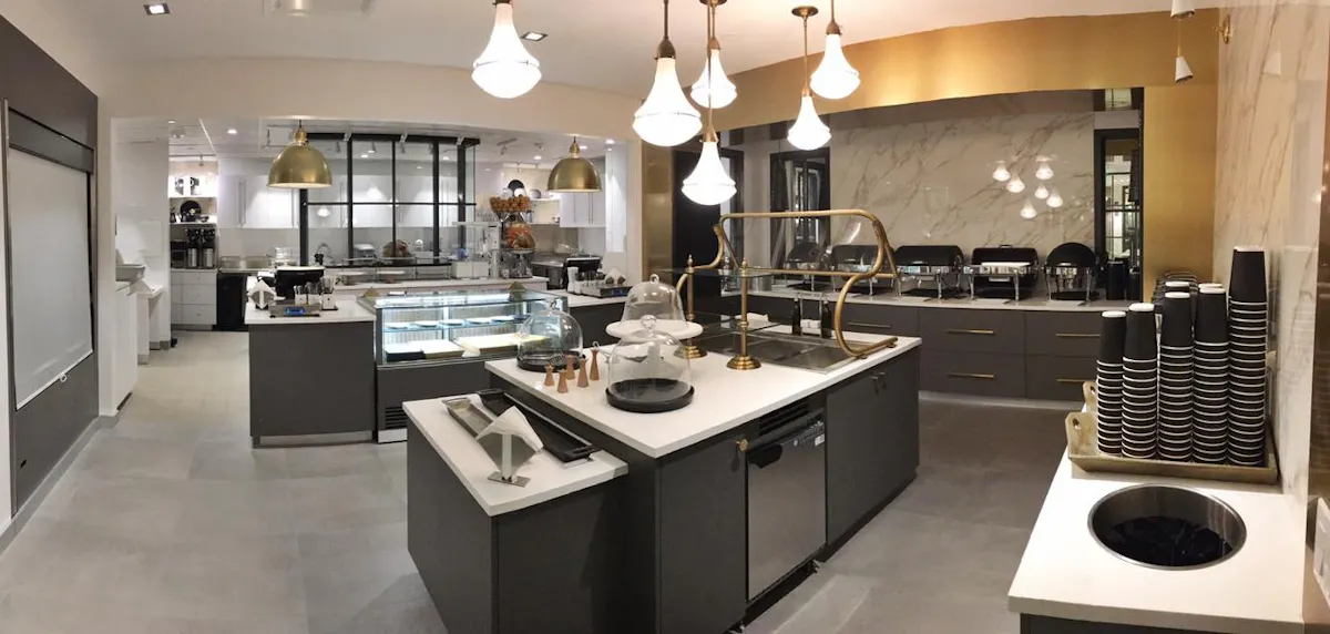 Interior shot of restaurant with white marble countertops, dark wood cabinets and modern pendant lights hanging above